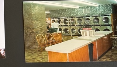 World O' Suds Coin Laundry, 430 E Main St Apopka FL — vintage photo of folding tables and chairs with a row of dryers along the brick wall