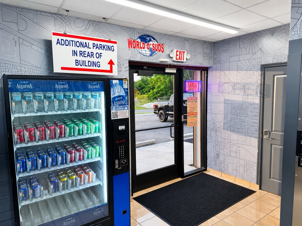 World O' Suds Coin Laundry, 430 E Main St Apopka FL — entrance lobby with Aquafina vending machine and World O' Suds logo